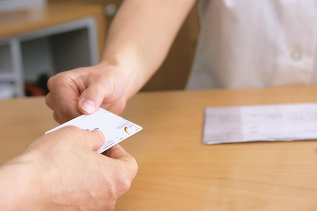 Hand holding out health insurance card