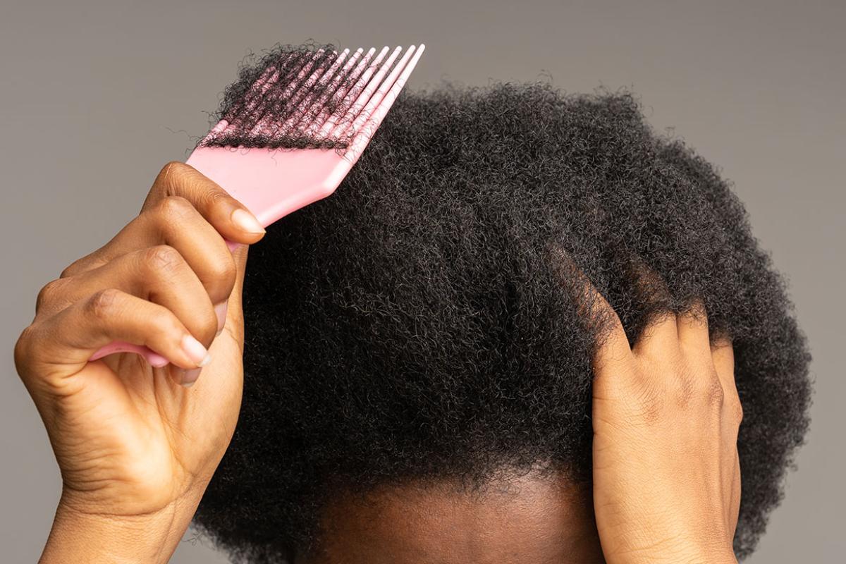 Hand holding hairbrush at head 