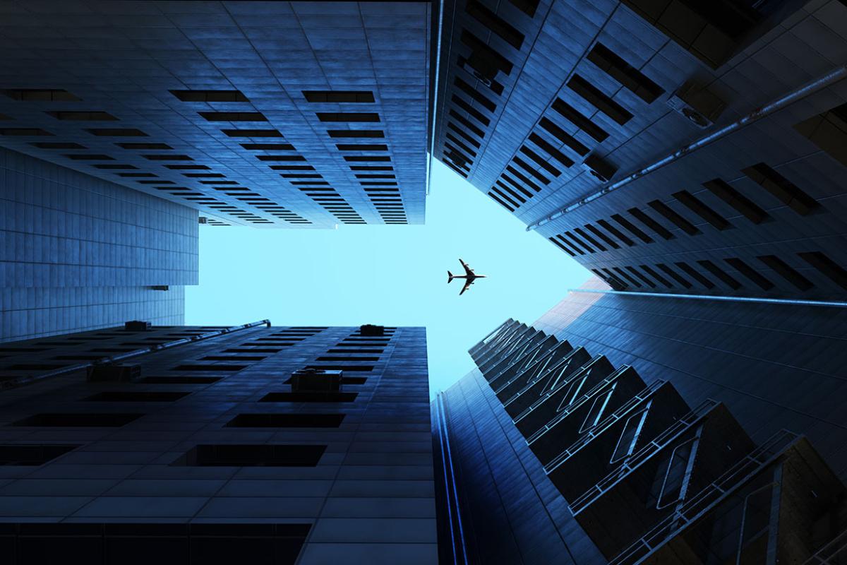 Buildings making arrow sign with airplane flying
