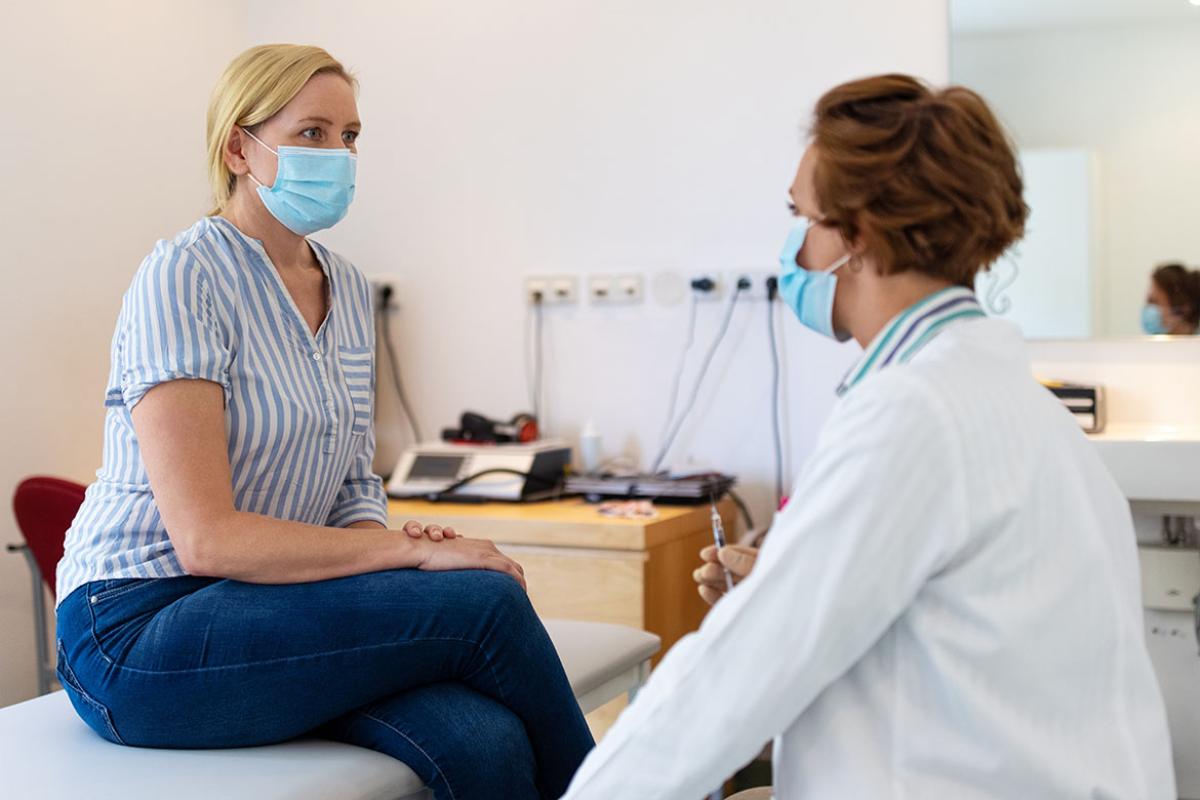 Physician and patient in exam room with masks