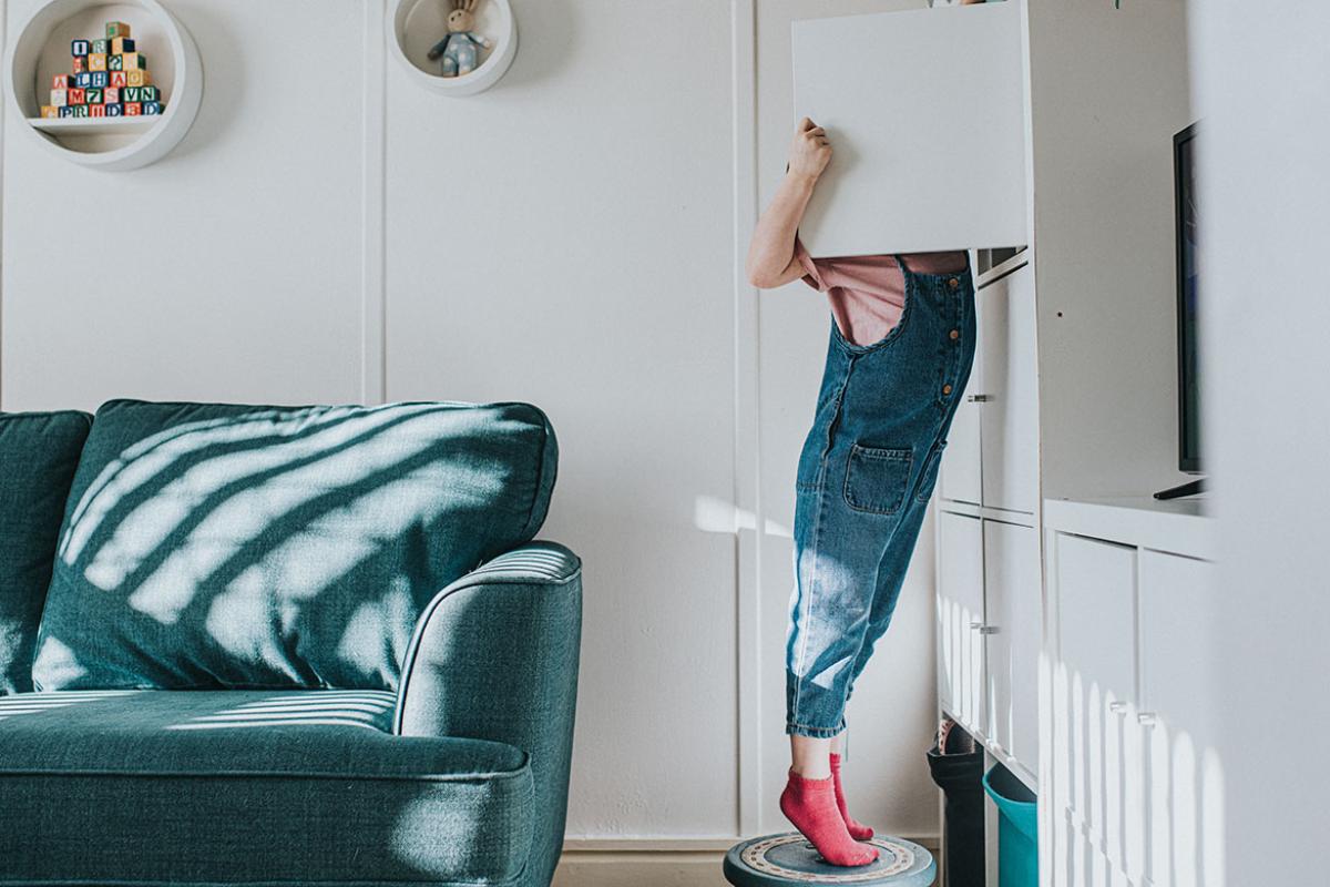 Young person reaching into high cabinet