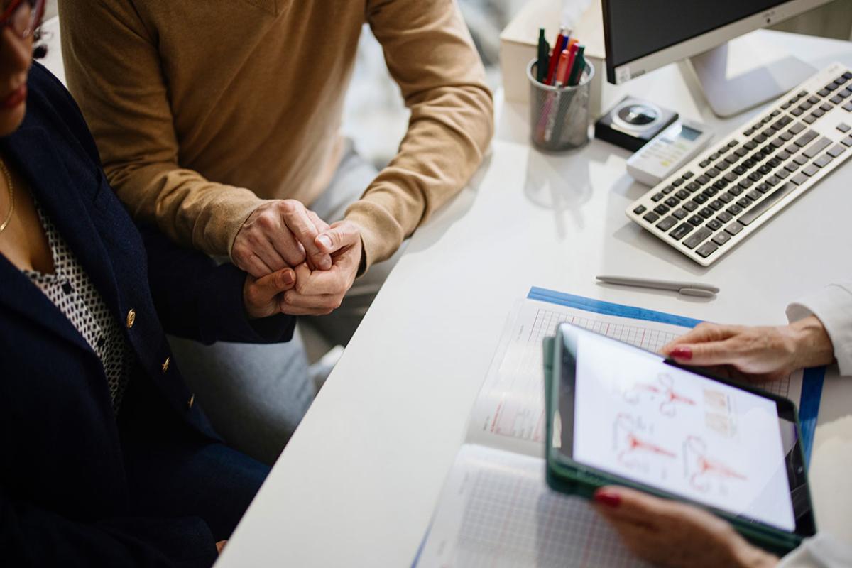 Couple holding hands, in discussion with health care worker