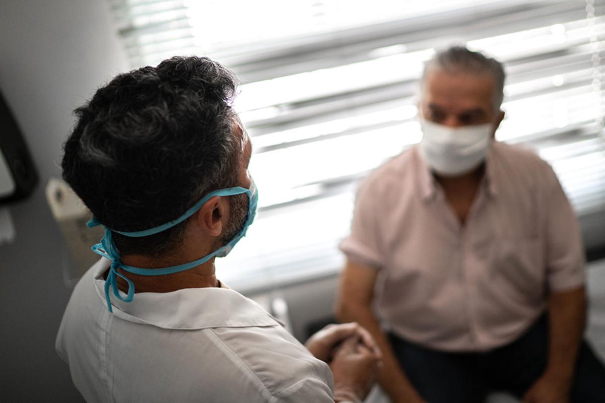 Standing physician speaking with seated patient