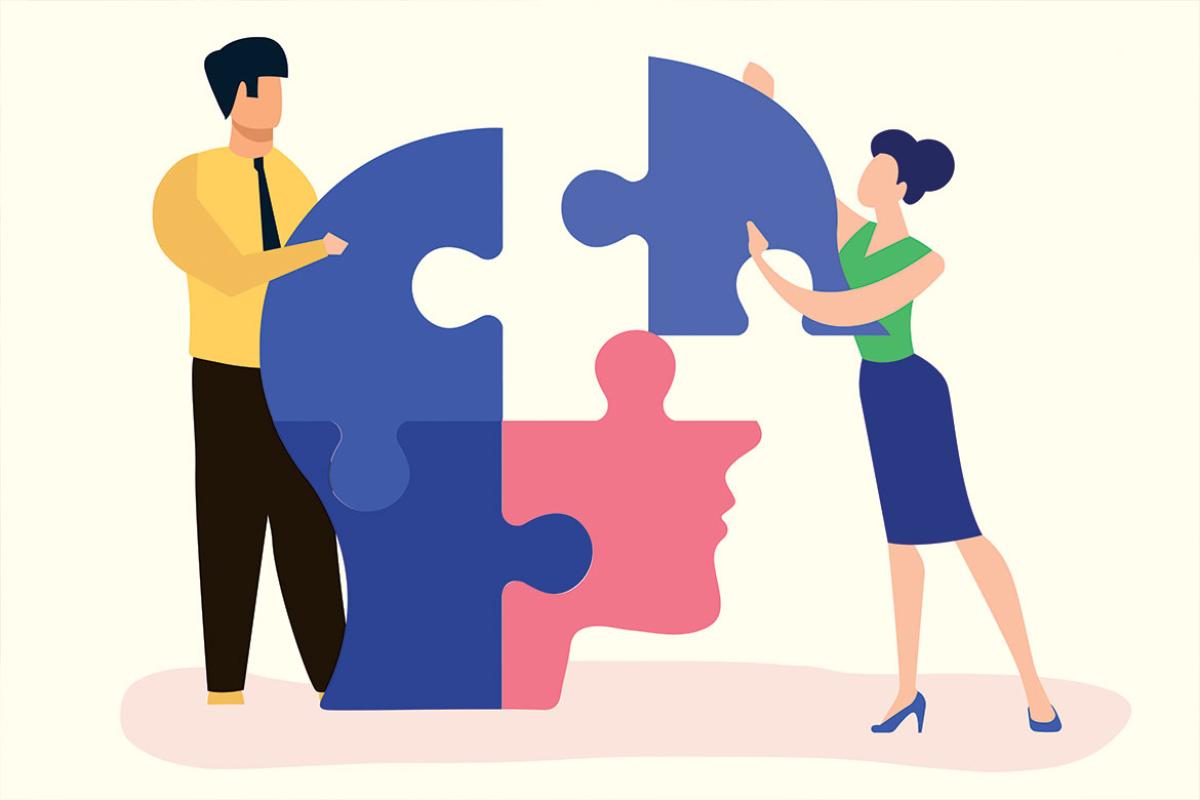 Two figures putting together puzzle in the shape of human head