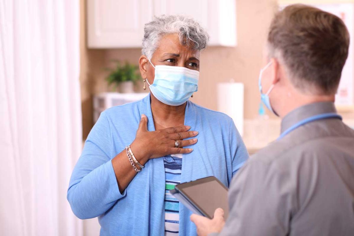 Person with hand on chest speaking with health care worker