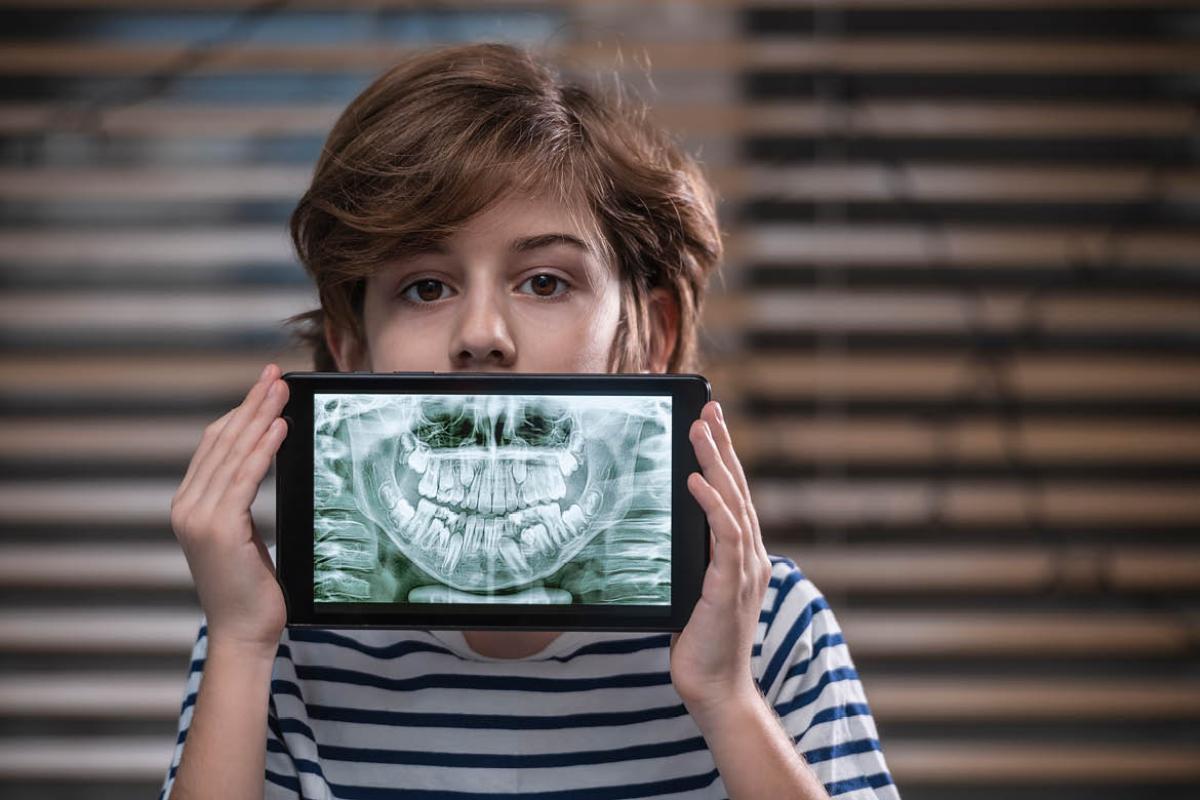 Child holding tablet with a picture of x-ray teeth