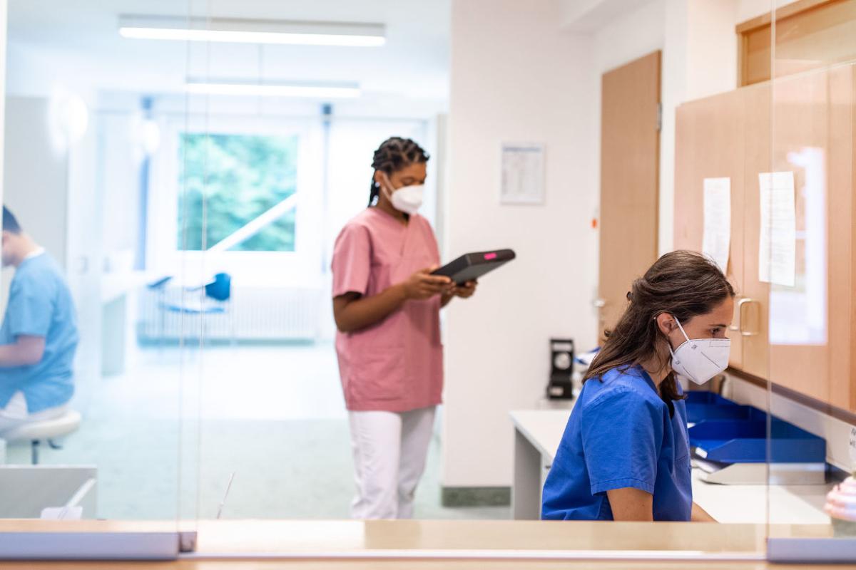 Clinic receptionist wearing protective face partition on the front desk