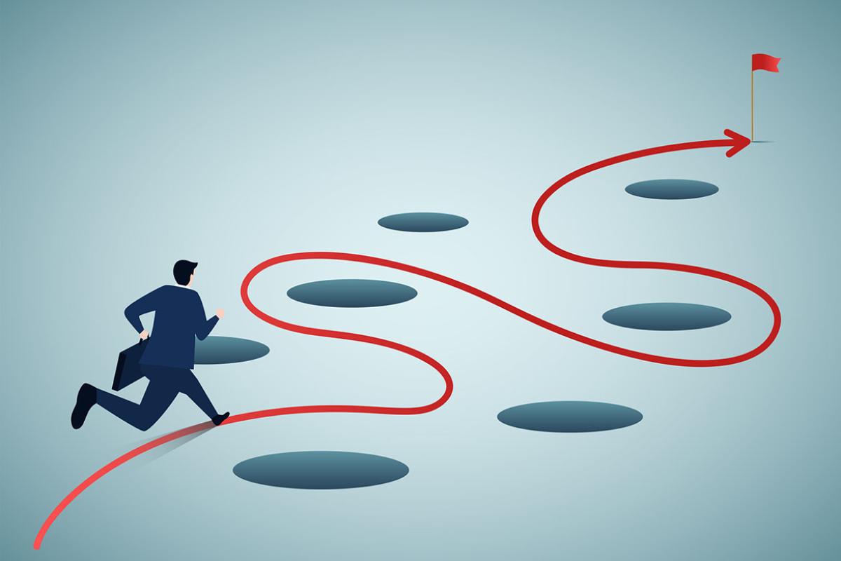 Person navigating holes in the ground on the way to an end destination of a flag