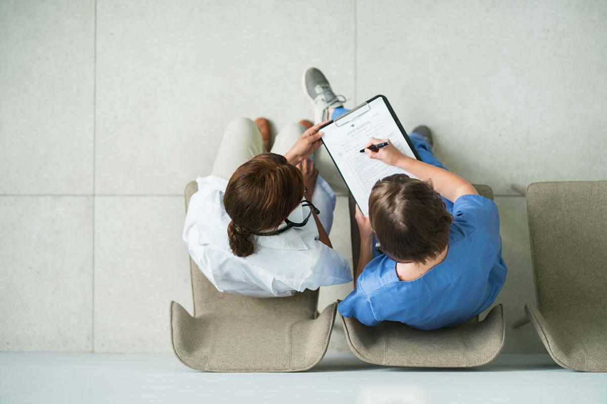 Two seated health care workers looking at a clipboard