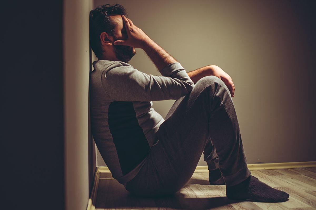 Person with hand on head sitting on the floor