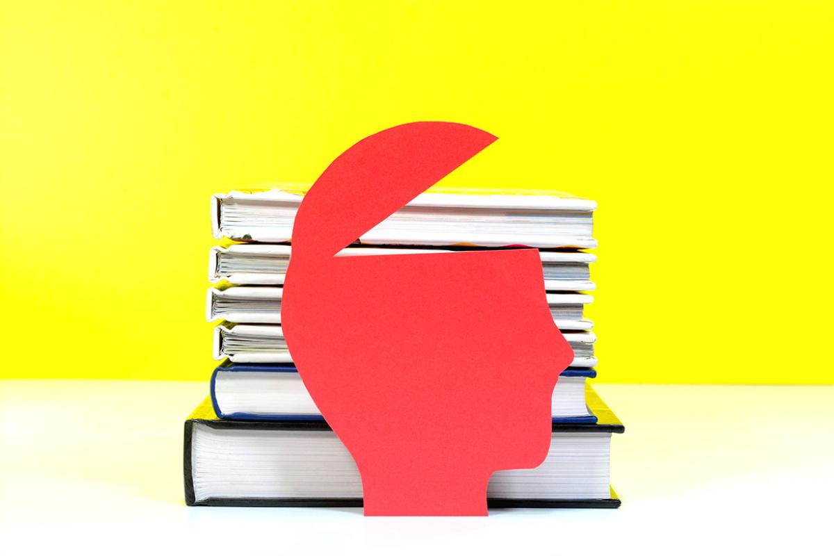 A model of a open head in front of a stack of books