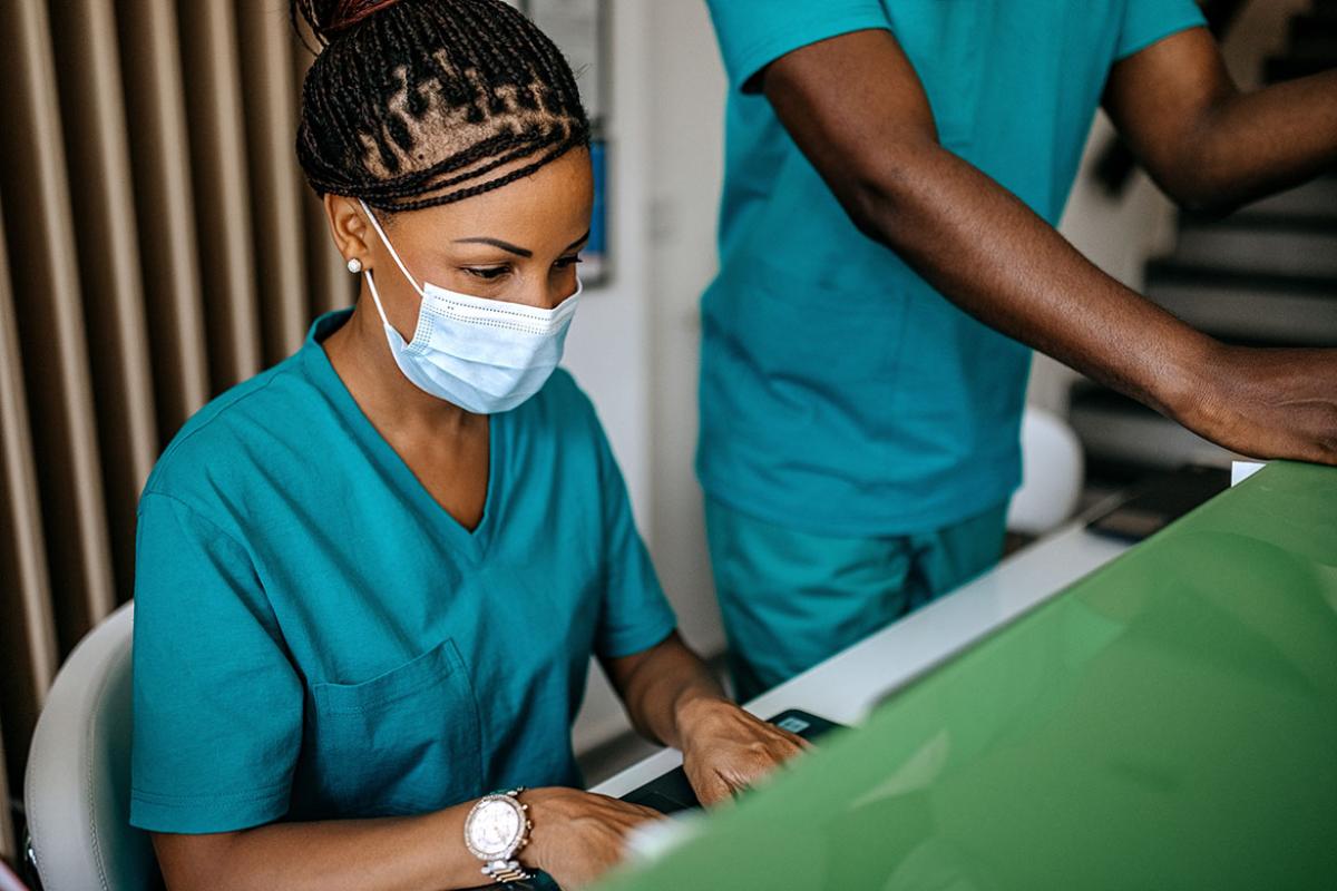 Medical assistant with face mask sitting at computer