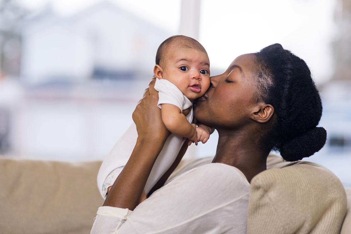 Mother holding and kissing smiling baby