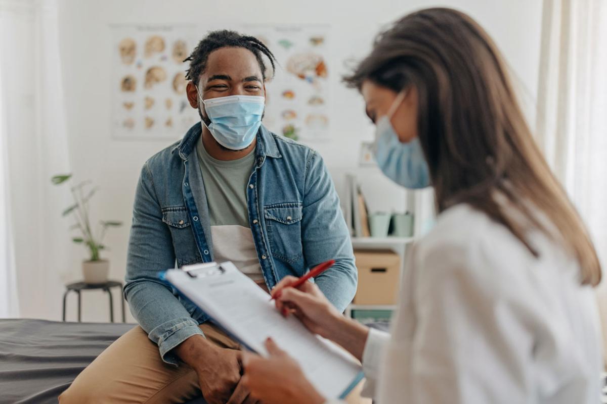 Physician taking notes while talking to patient