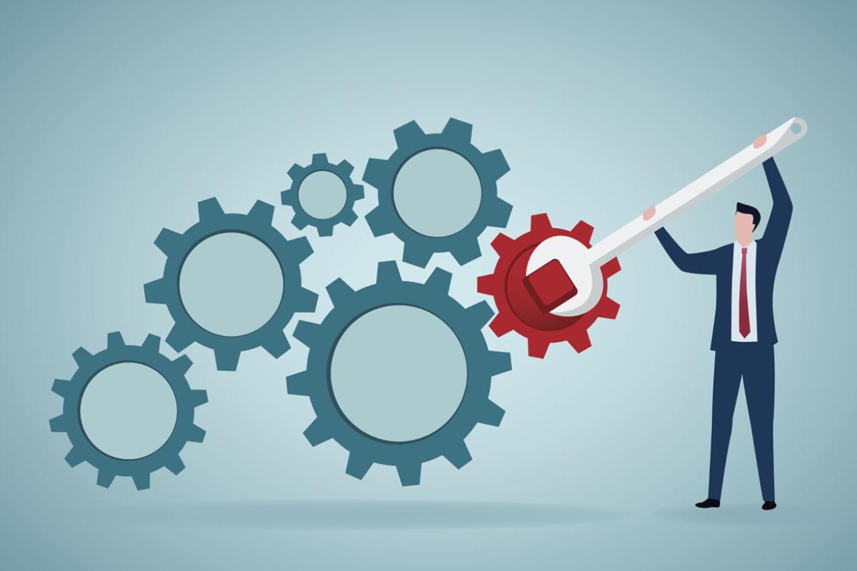 Businessperson with wrench and cogs fixing gear