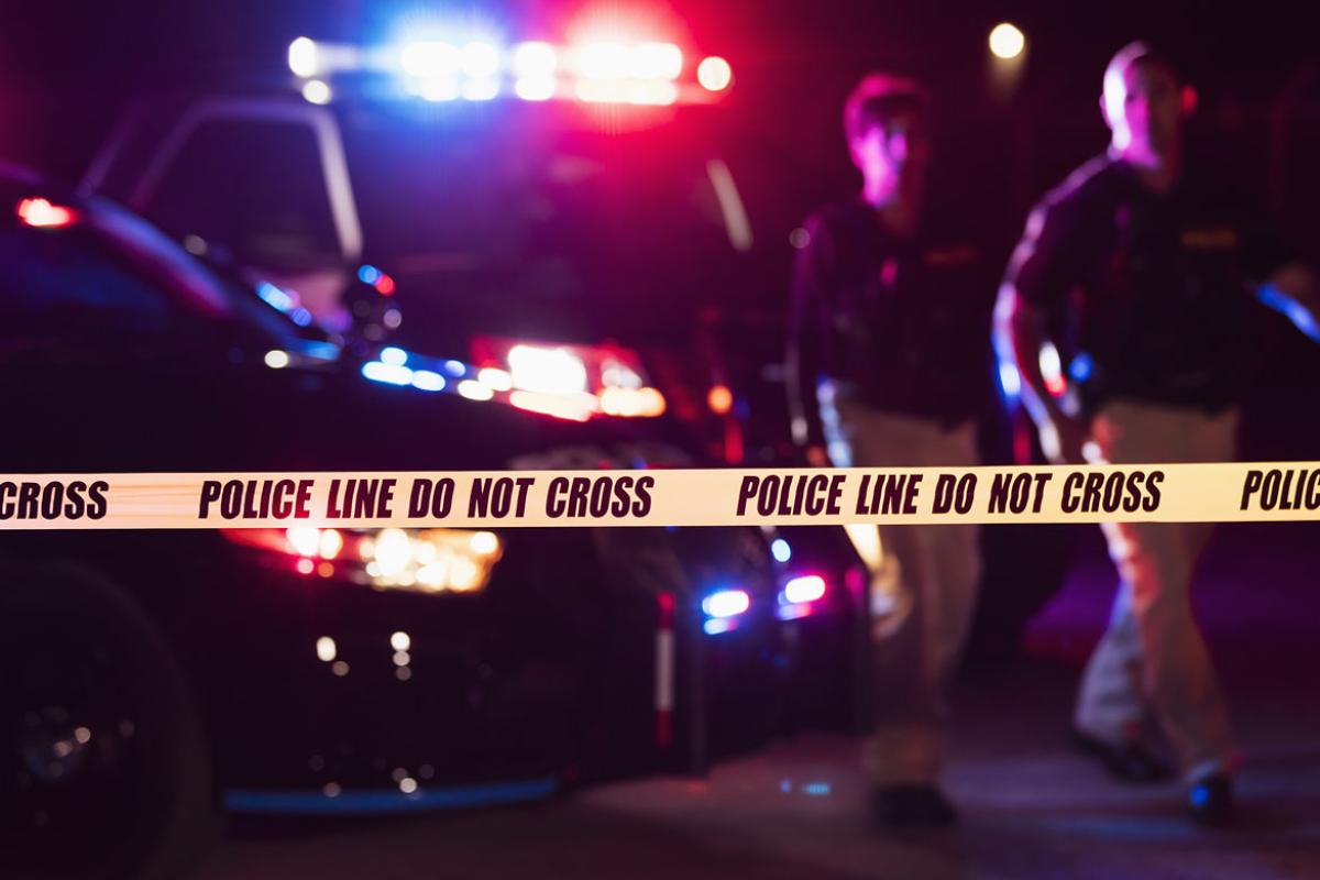 Crime scene yellow tape with police in background