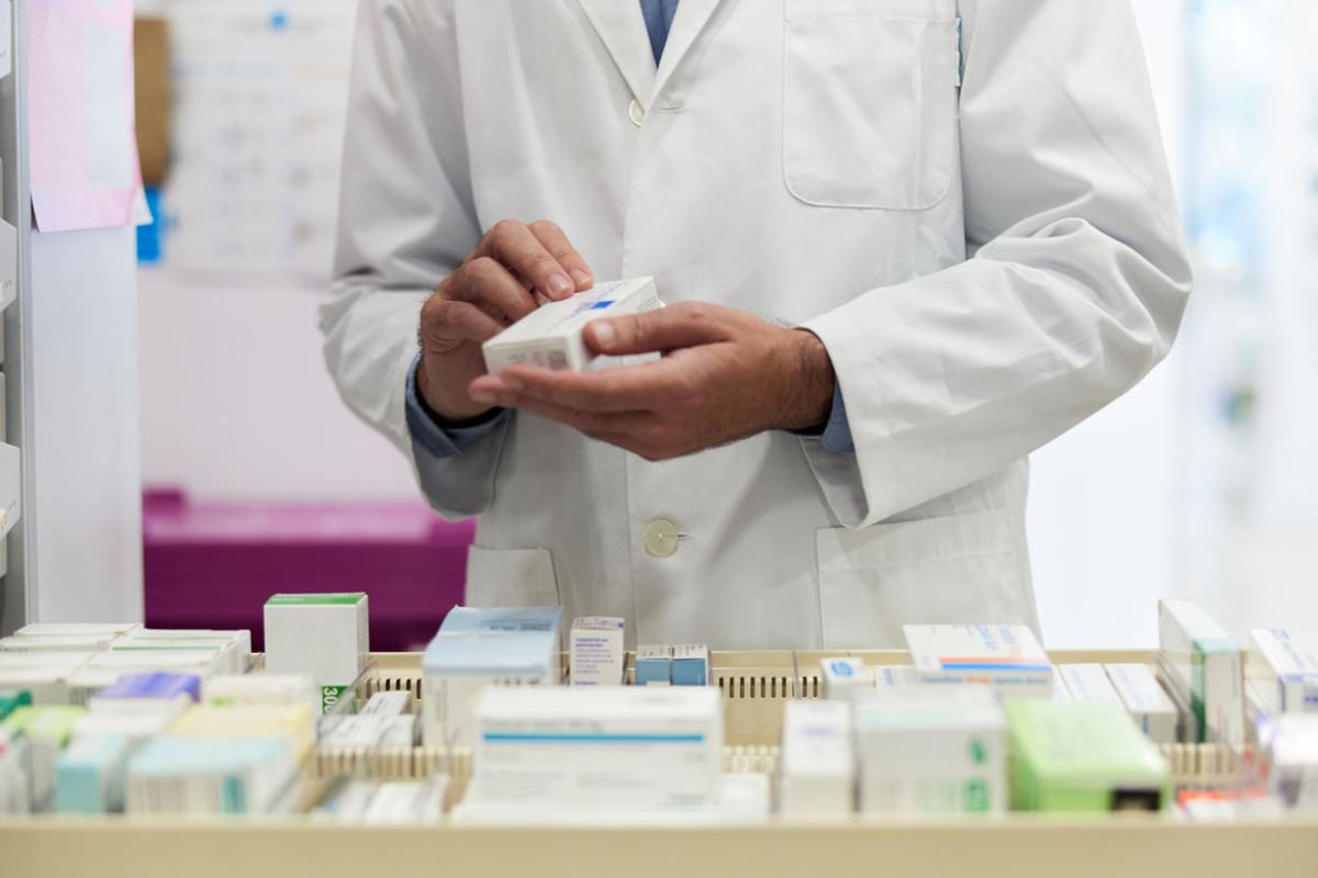 Pharmacist organizing pillboxes in a drugstore drawer