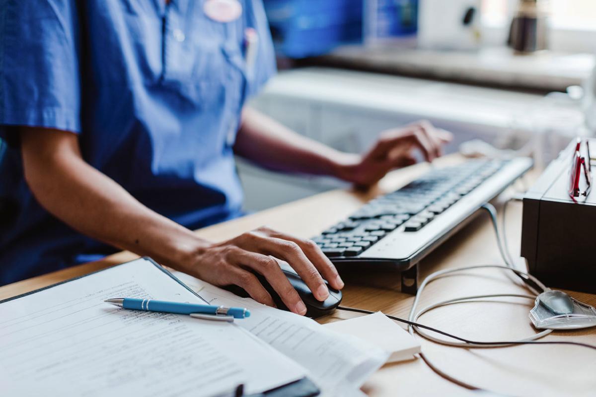 Health care worker using computer at desk in hospital 