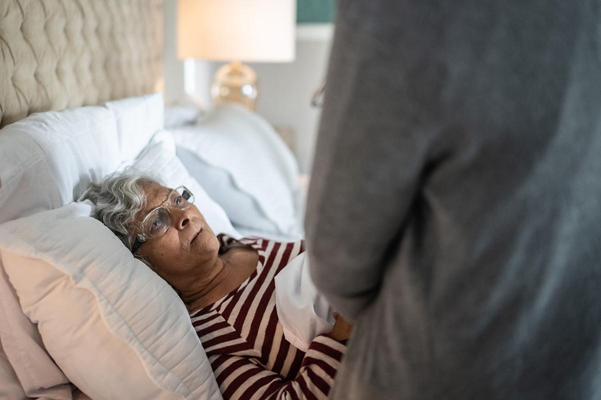 Woman in bed being attended to by a health care worker