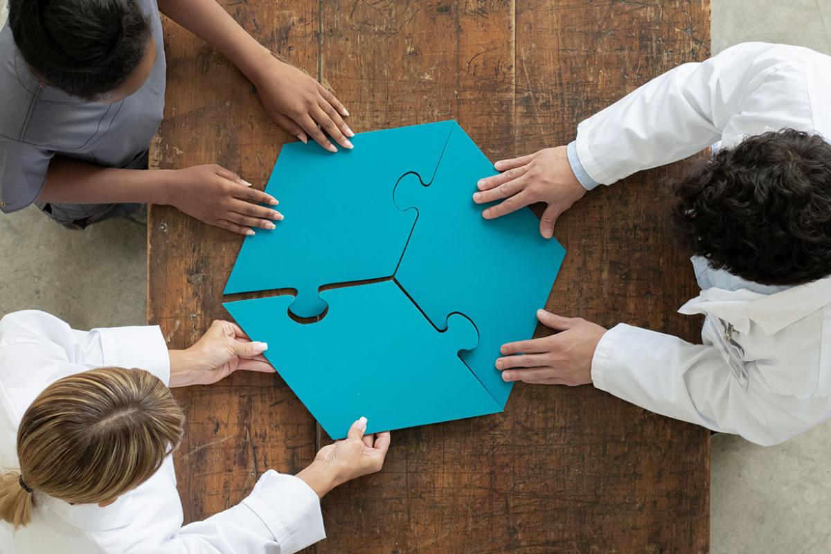 Three people assembling large puzzle pieces 