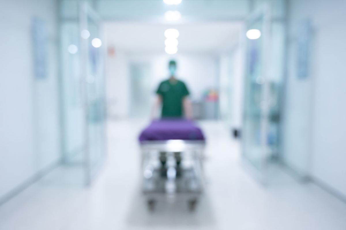 Health care worker pulling an emergency stretcher without patient at hospital c