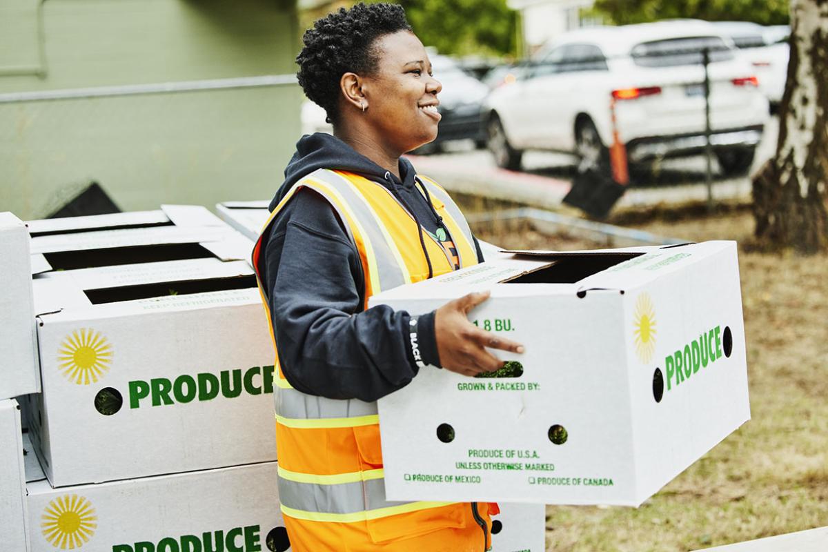 Smiling volunteer holding CSA box at community center