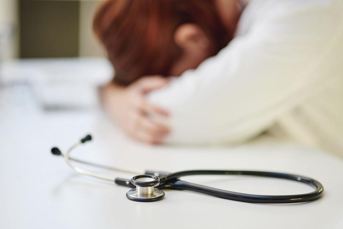 Physician sleeping at their desk with a stethoscope near by