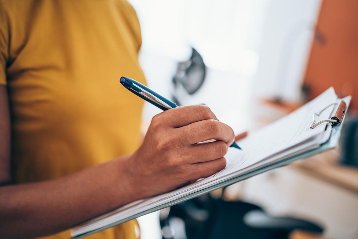 Person filling out a form on a clipboard