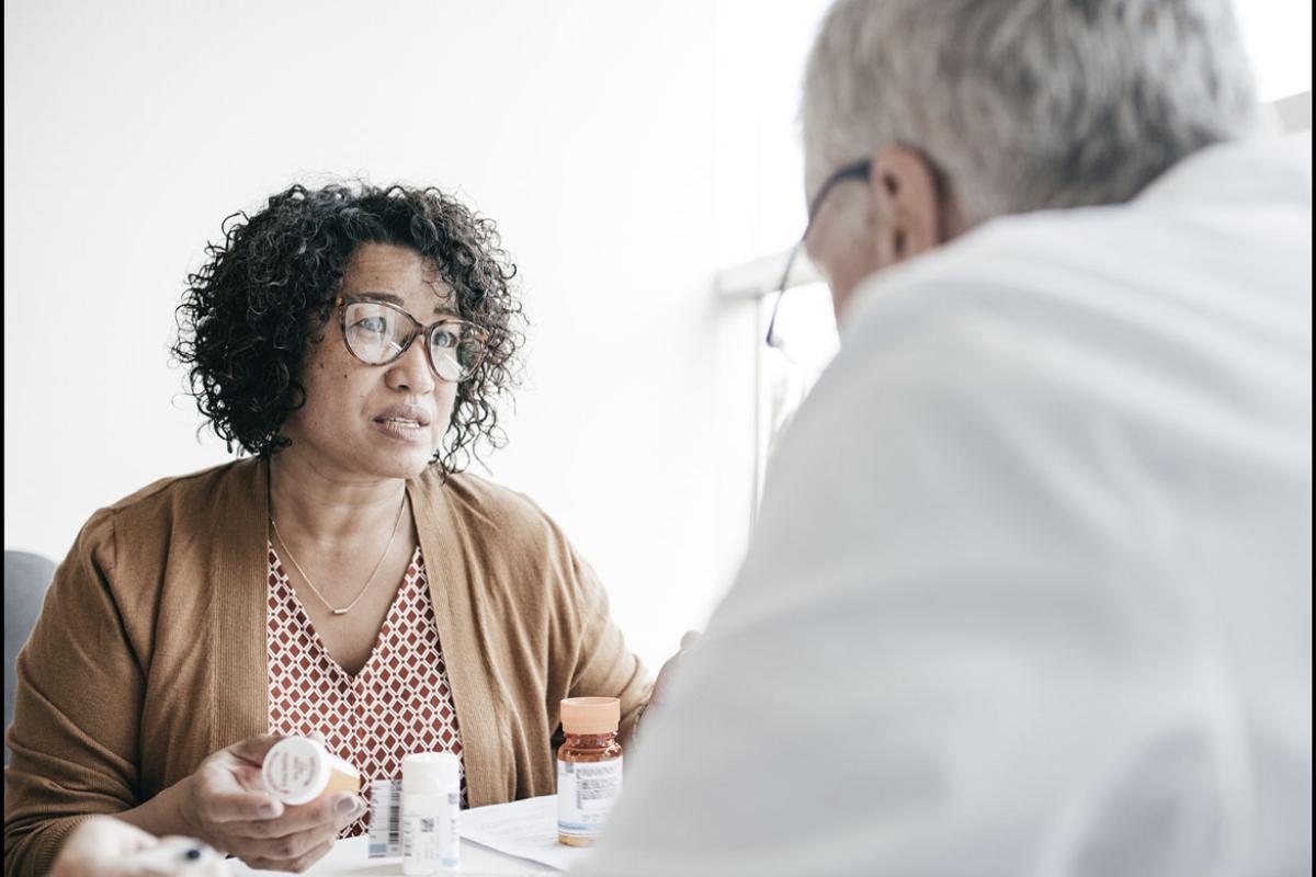Person holding medication and speaking with physician