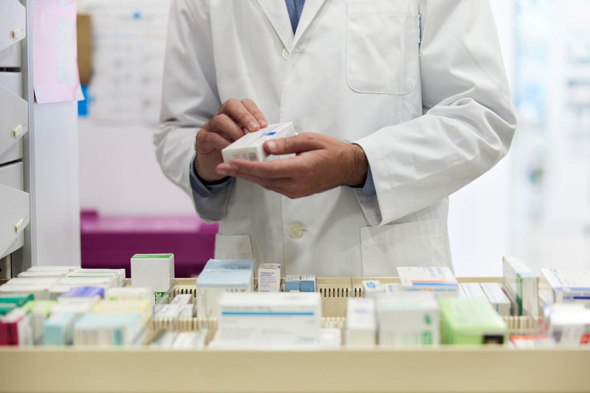 Pharmacist organizing pillboxes in a drugstore drawer