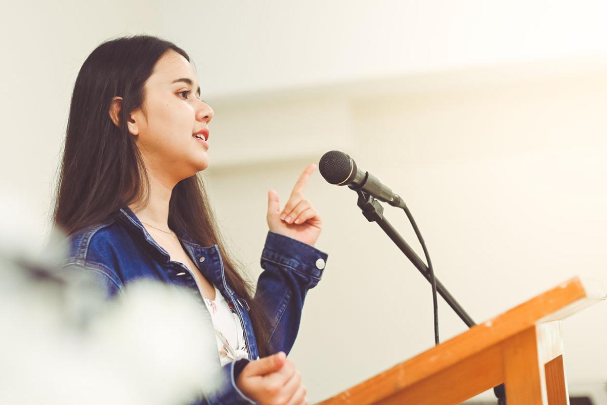Person speaking into a microphone at a podium
