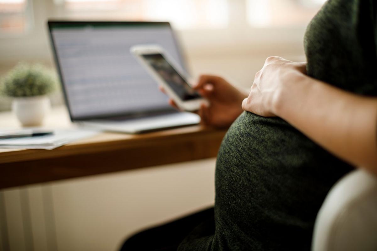 Pregnant person scrolling through a smartphone