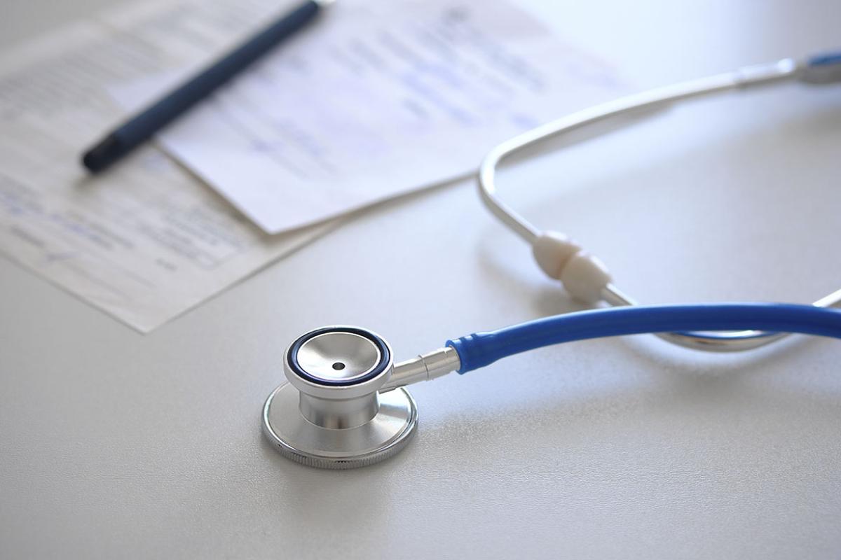 Stethoscope next to some papers and a pen