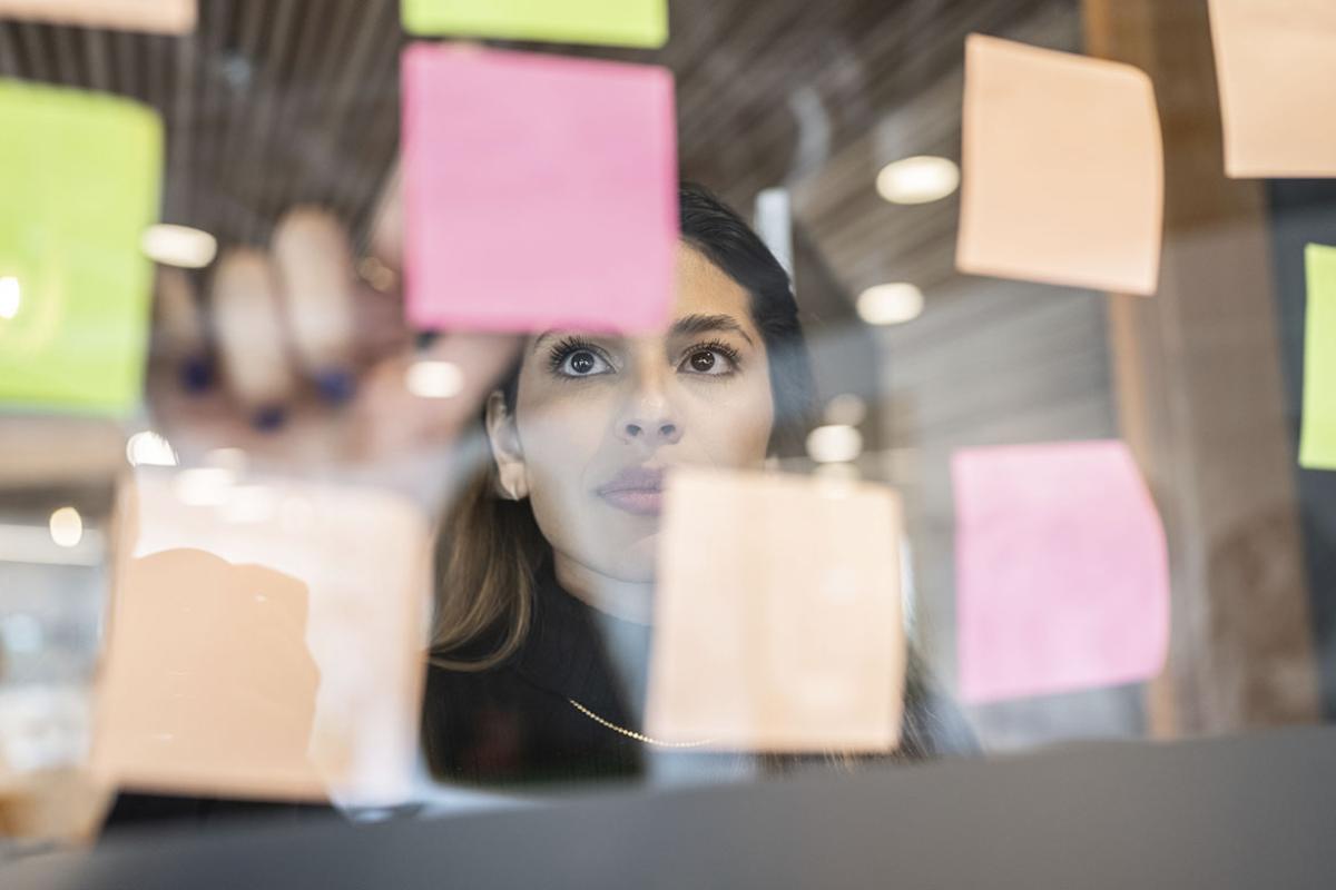 Person pointing at a sticky note on an office window