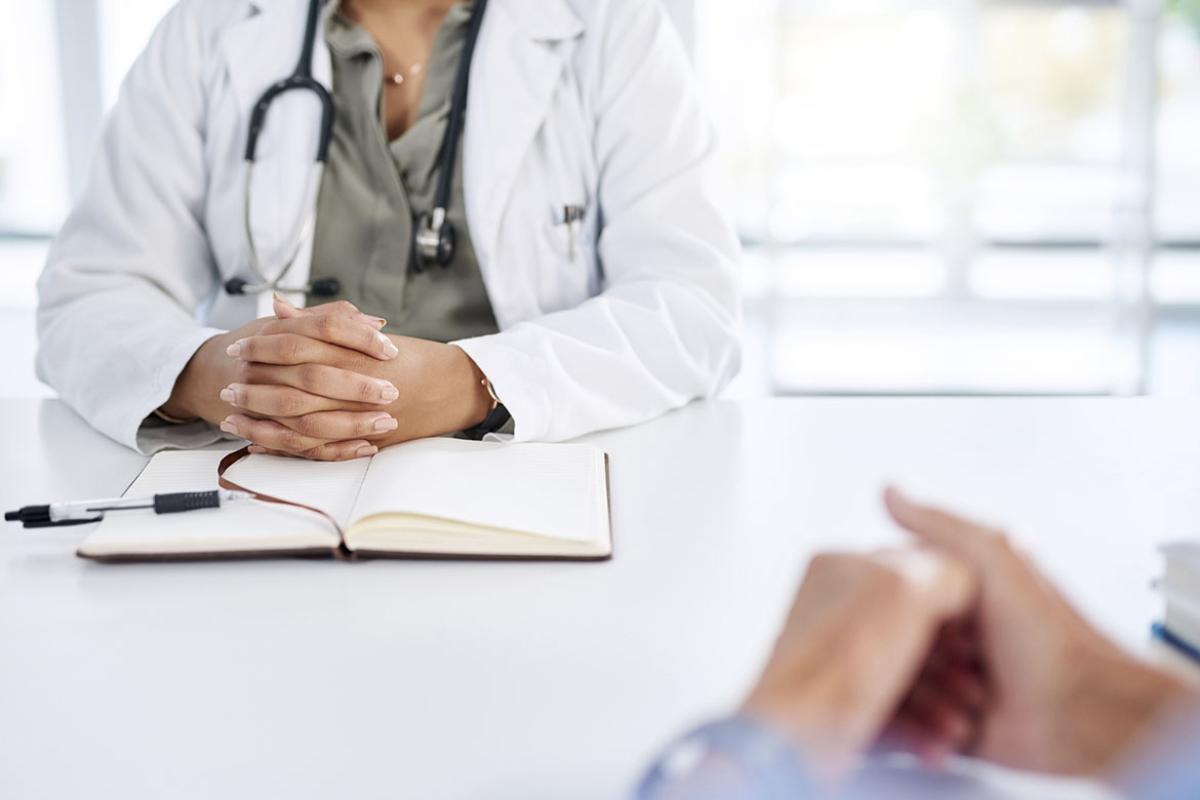 Physician with hands folded at a desk
