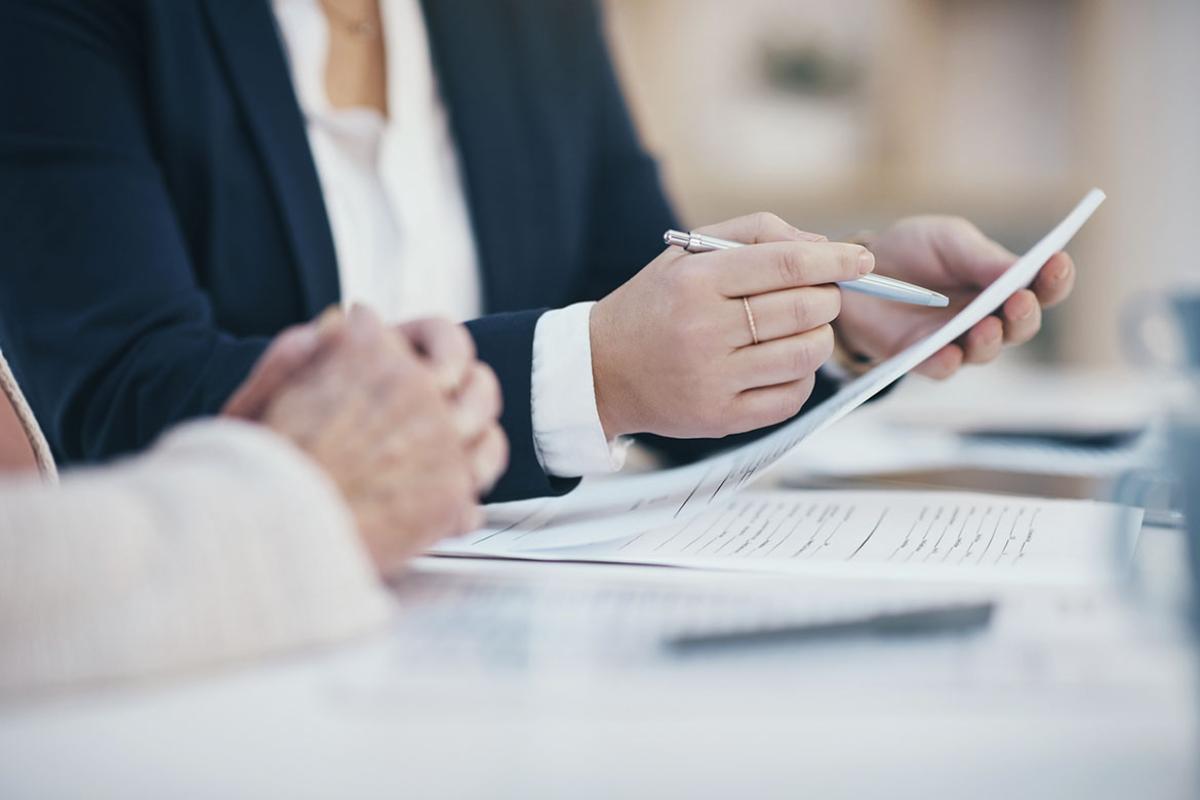 Person pointing at a document with a pen