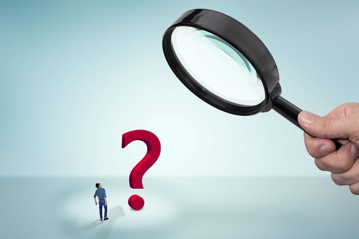 Figure and a question mark under a magnifying glass