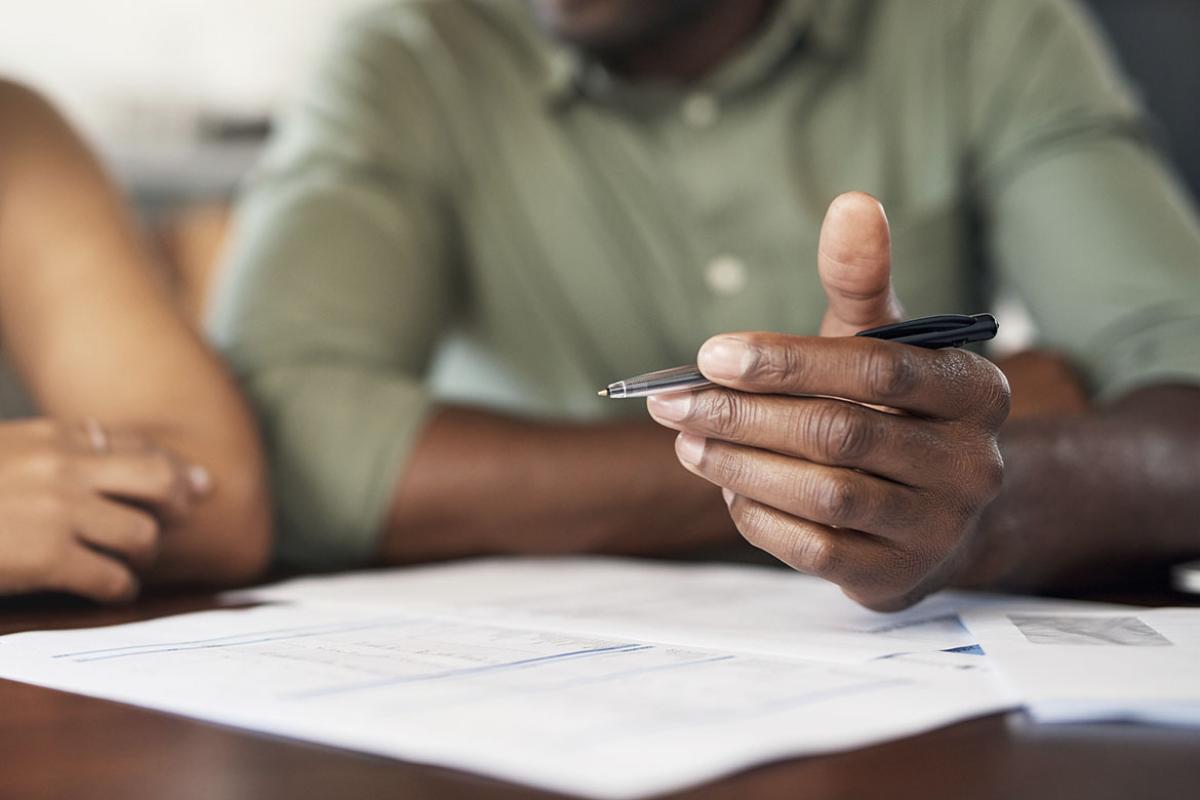 Person holding a pen over documents