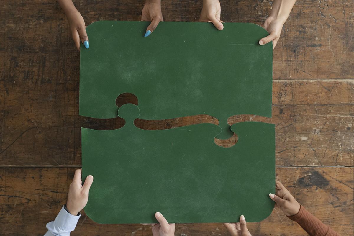 Hands putting together two large puzzle pieces