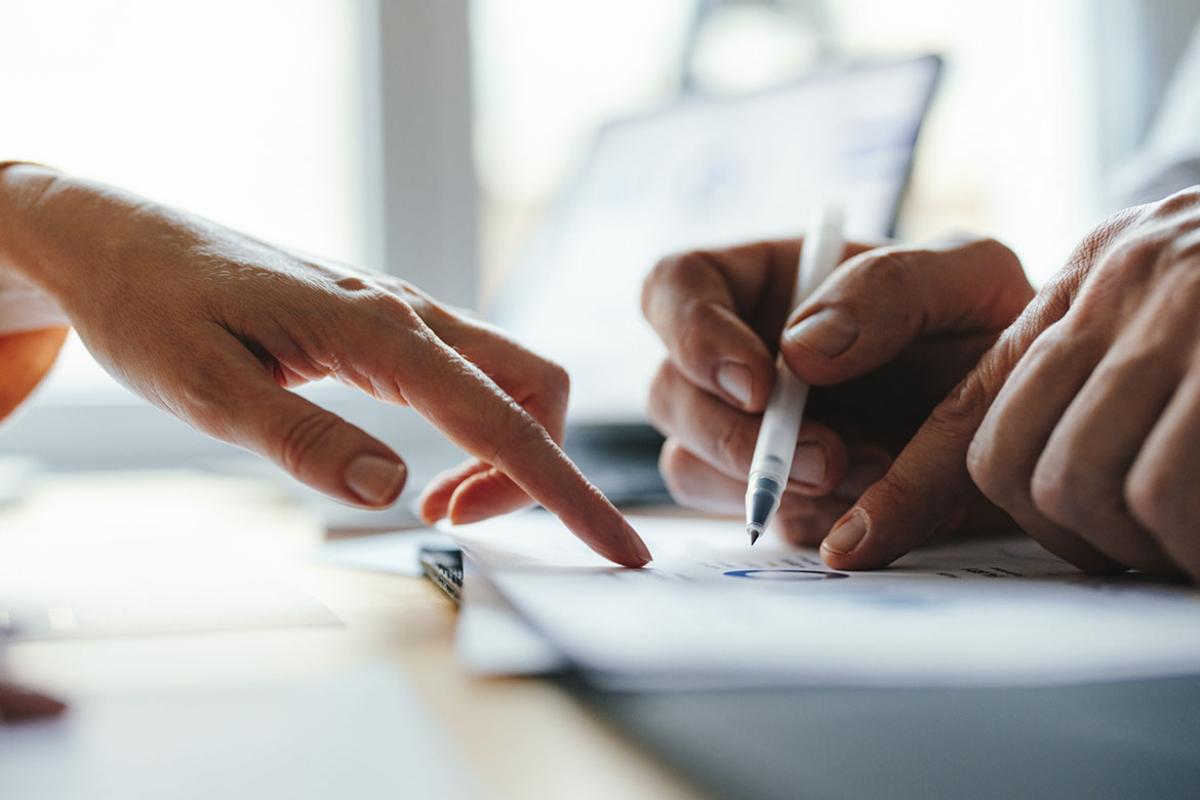 Hands pointing at business graphs and documents together