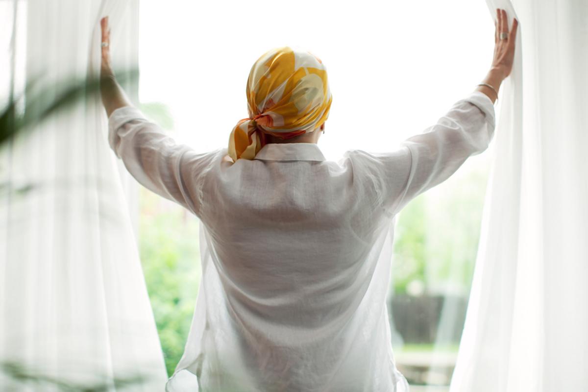 Person wearing a headscarf looking out a window