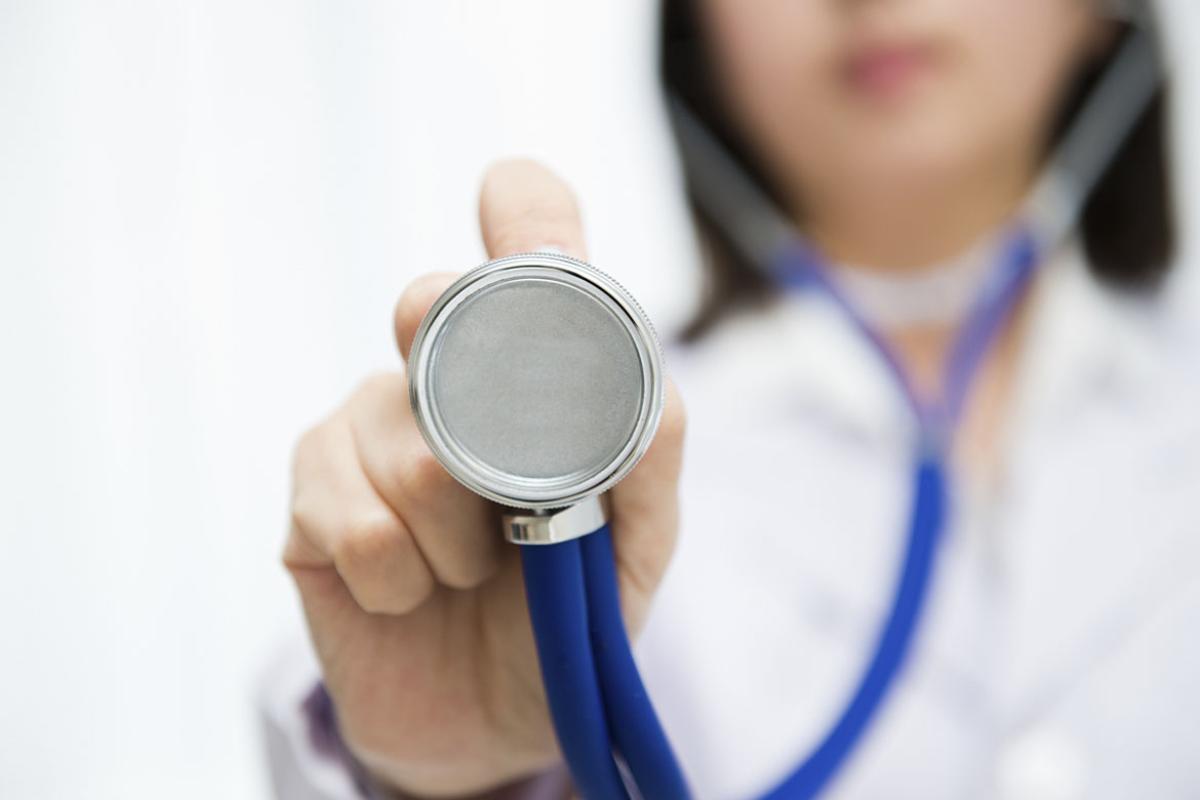A doctor holds a stethoscope up