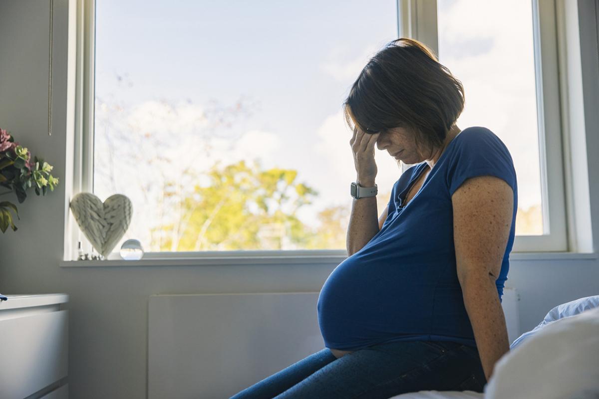 Pregnant woman with hand over eyes