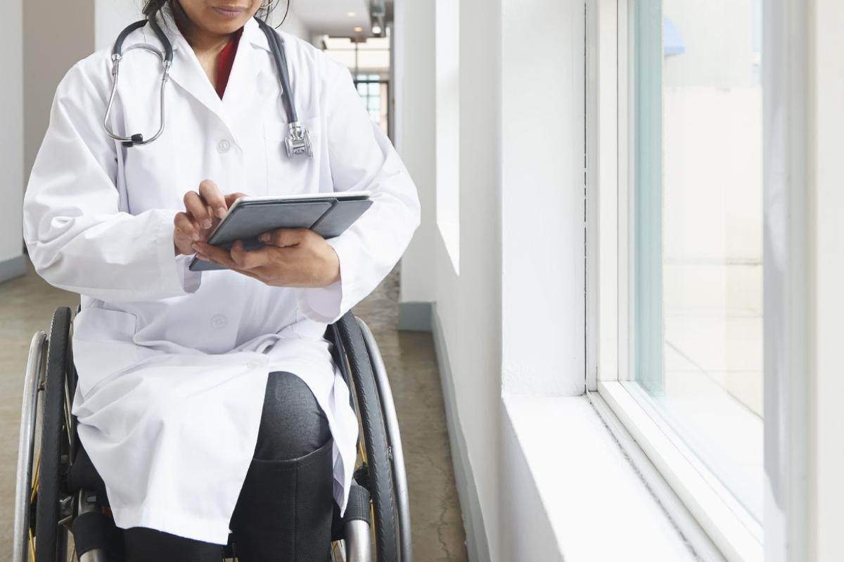 Physician in a wheelchair using digital tablet