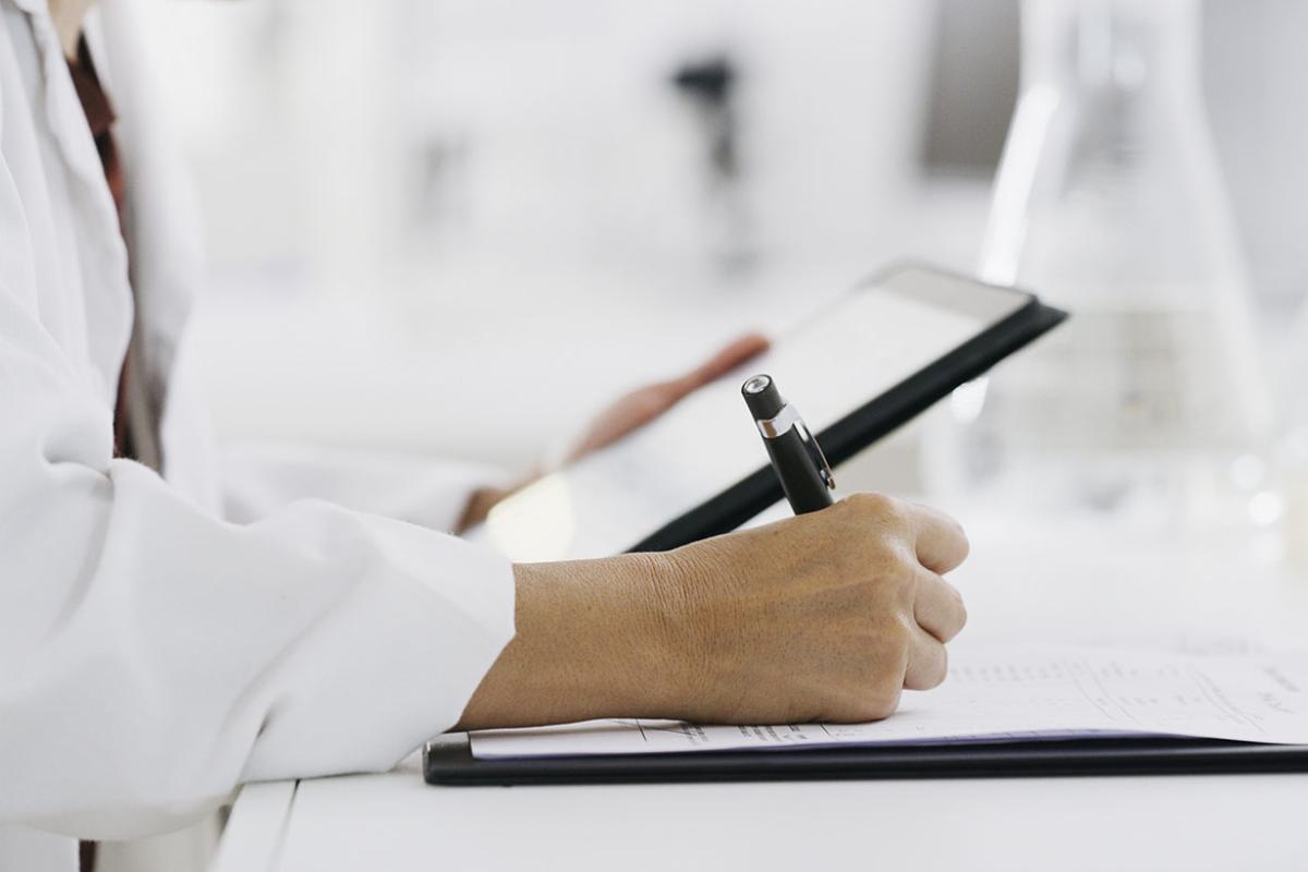 Person holding a tablet in one hand and writing with another