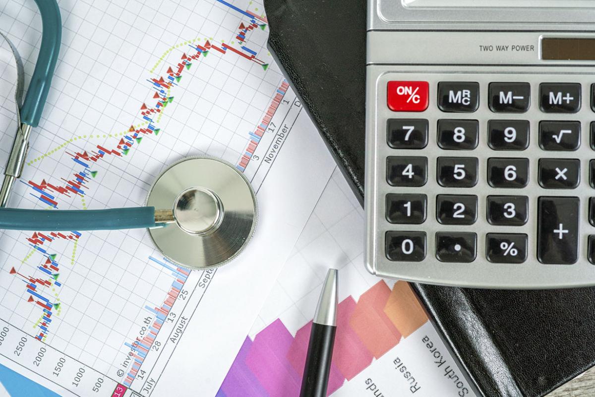 Stethoscope on a report with data with a calculator and pen nearby