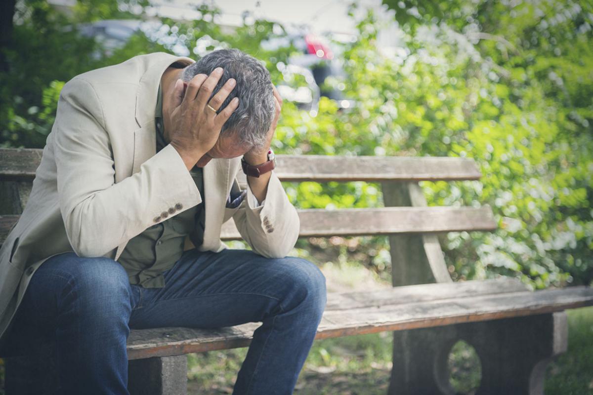 Person sitting on a park bench, head in hands