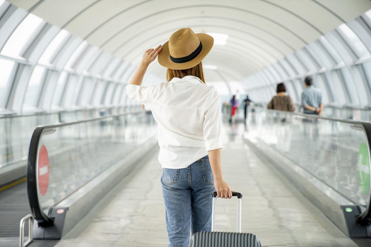 Young casual traveler with suitcase at airport