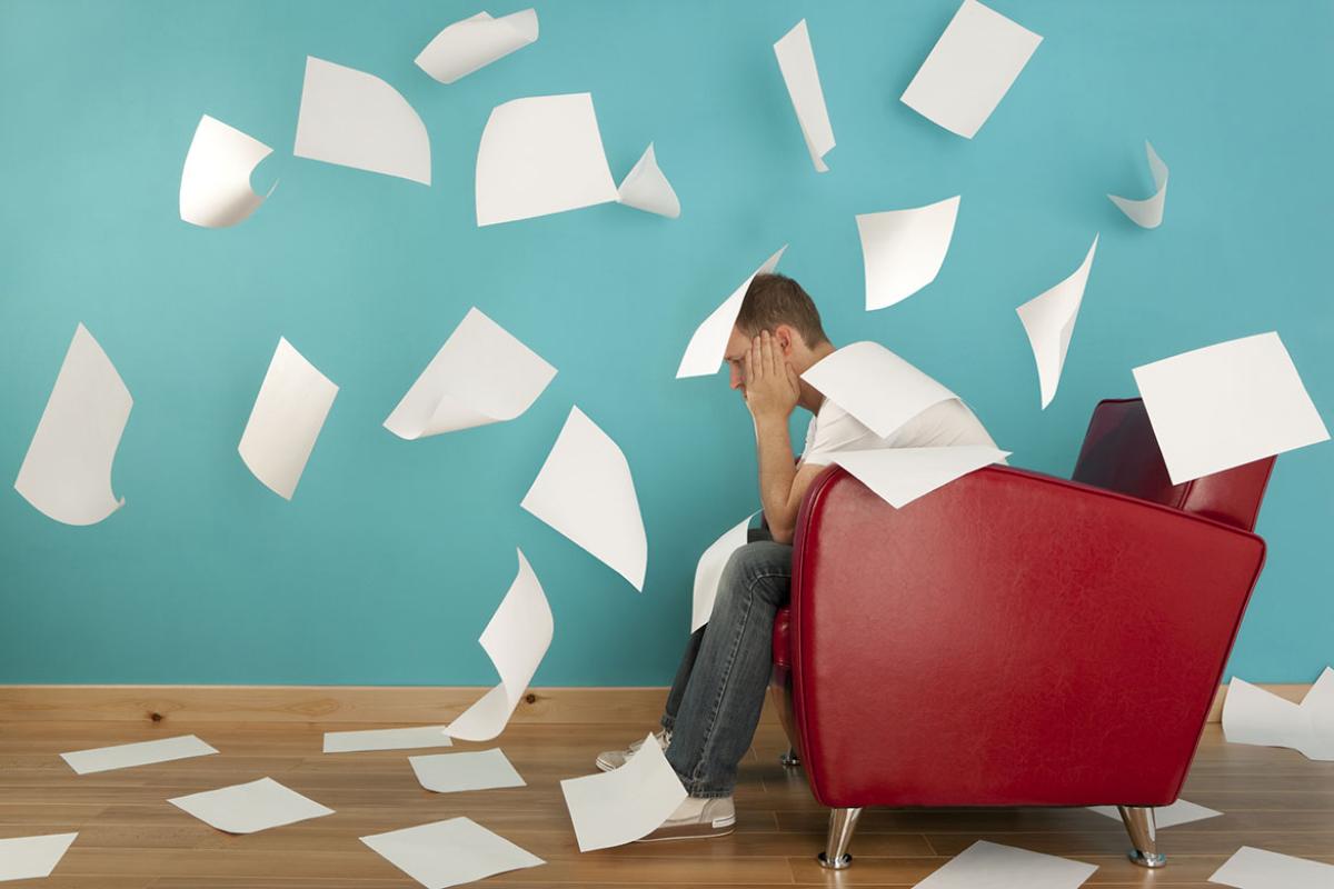 Person sitting in chair surrounded by pieces of paper