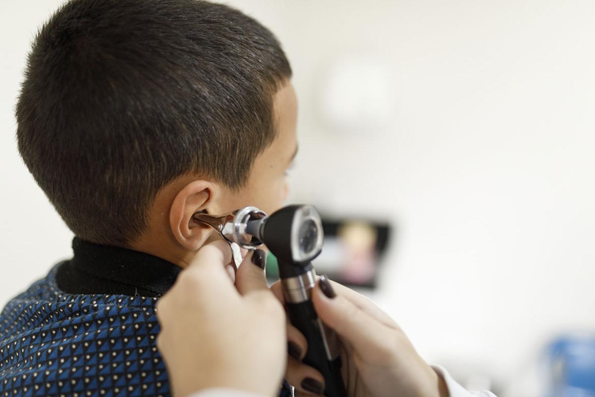 Doctor checking little boy's ears with an otoscope